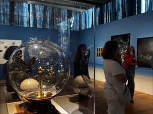 Le planétaire d’Émile Bertaux exposé au Mucem, sous vitrine, dans une salle bleue avec visiteurs observant l’objet et d’autres instruments astronomiques.