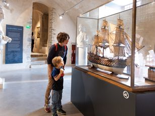 Enfant dans le musée  Enfant et sa mère face à la vitrine d'une maquette