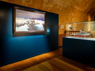 Vue d’une salle d’exposition présentant une peinture de paysages polaires et une maquette de navire océanographique, au musée national de la Marine.
