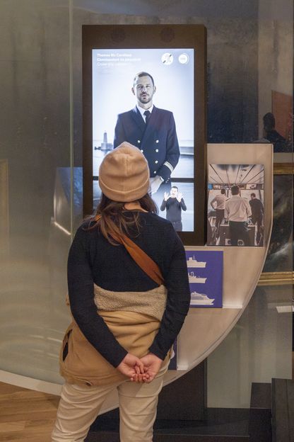 Jeune femme devant un écran d'interview d'un capitaine de paquebot