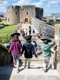 Enfants de dos portant un tricorne sur les remparts du château