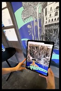 une personne regarde la fresque à travers une tablette tactile