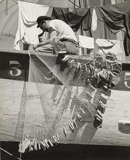 Photo en noir et blanc d'un pêcheur et son filet