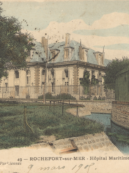 Carte postale ancienne colorisée montrant l’Hôpital Maritime de Rochefort-sur-Mer : un grand bâtiment en pierre à toits mansardés et fenêtres à frontons, bordé d’une pelouse et d’un canal au premier plan, protégé par une grille en fer forgé. En bas, la légende imprimée « 49 – ROCHEFORT-sur-MER – Hôpital Maritime » et une écriture manuscrite datée « 9 mars 1908 » sur la marge droite.